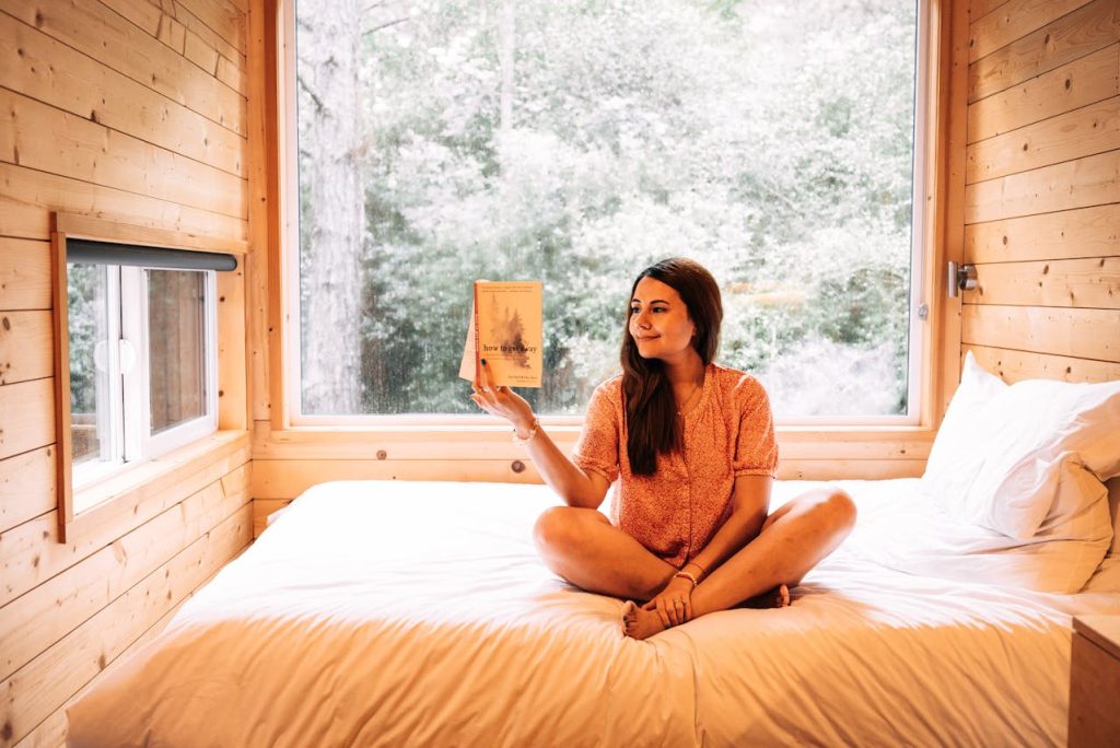 A Woman Reading a Book while Sitting on the Bed