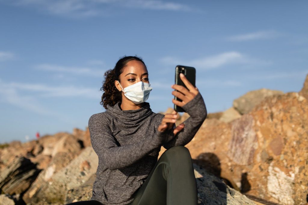 Woman in Gray Sweater Holding Black Smartphone