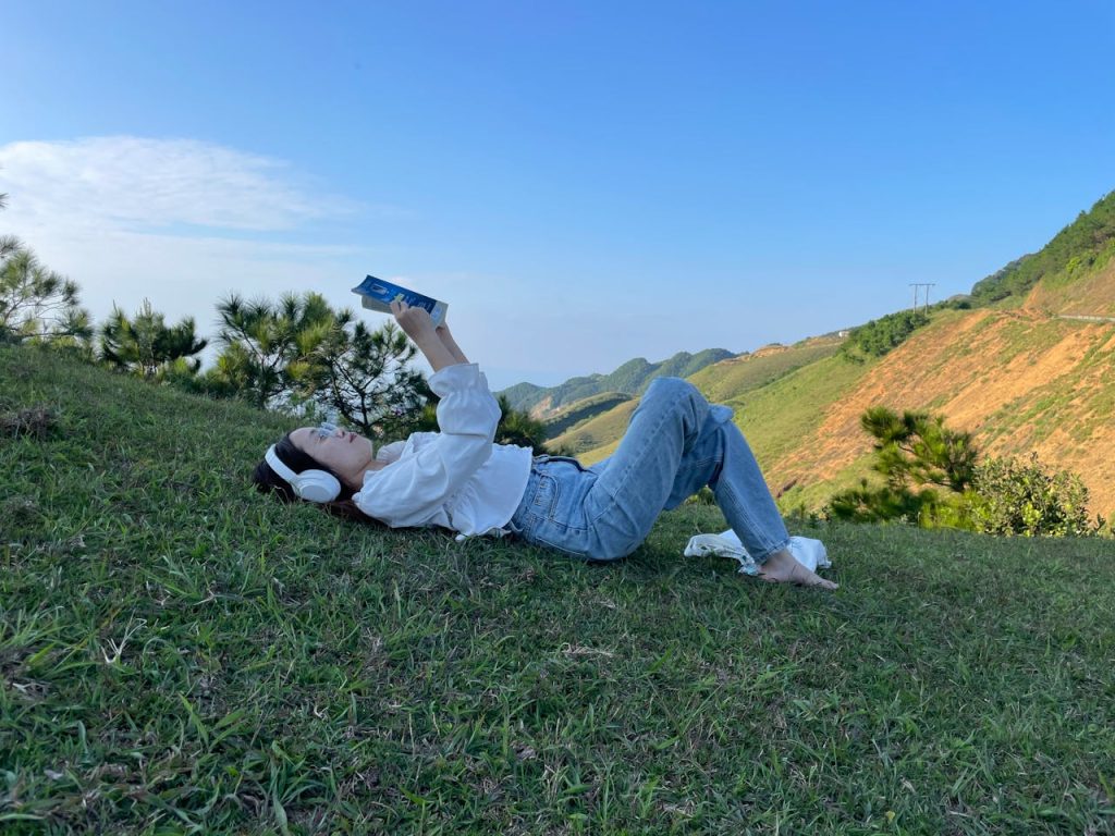 Woman Lying Down in Headphones and Reading Book