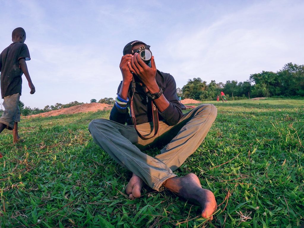 Man Sitting on Grass While Taking Photo