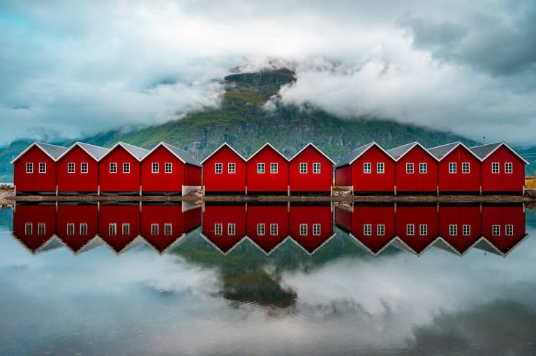 Scenic Reflection of Red Cabins on a Norwegian Fjord