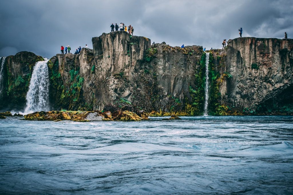 People Near Cliff Under Cloudy Sky