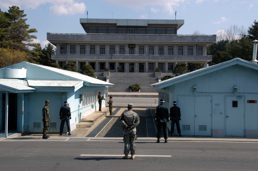  A view from South Korea towards North Korea in the Joint Security Area at Panmunjom. North and South Korean military personnel, as well as a single US soldier, are shown.