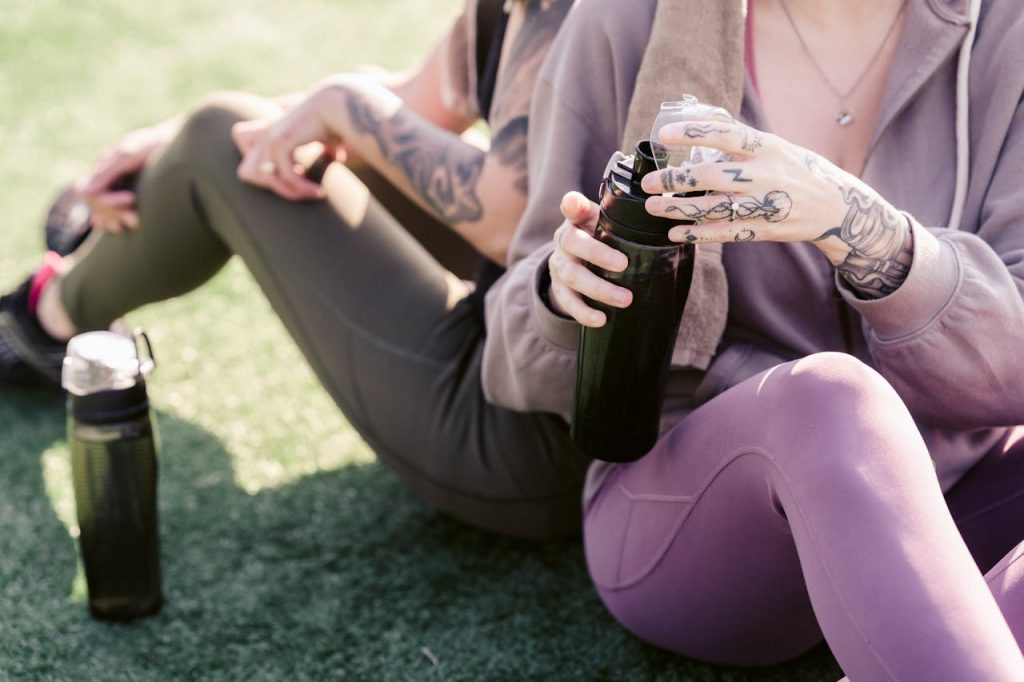 Crop women in sportswear resting on green lawn